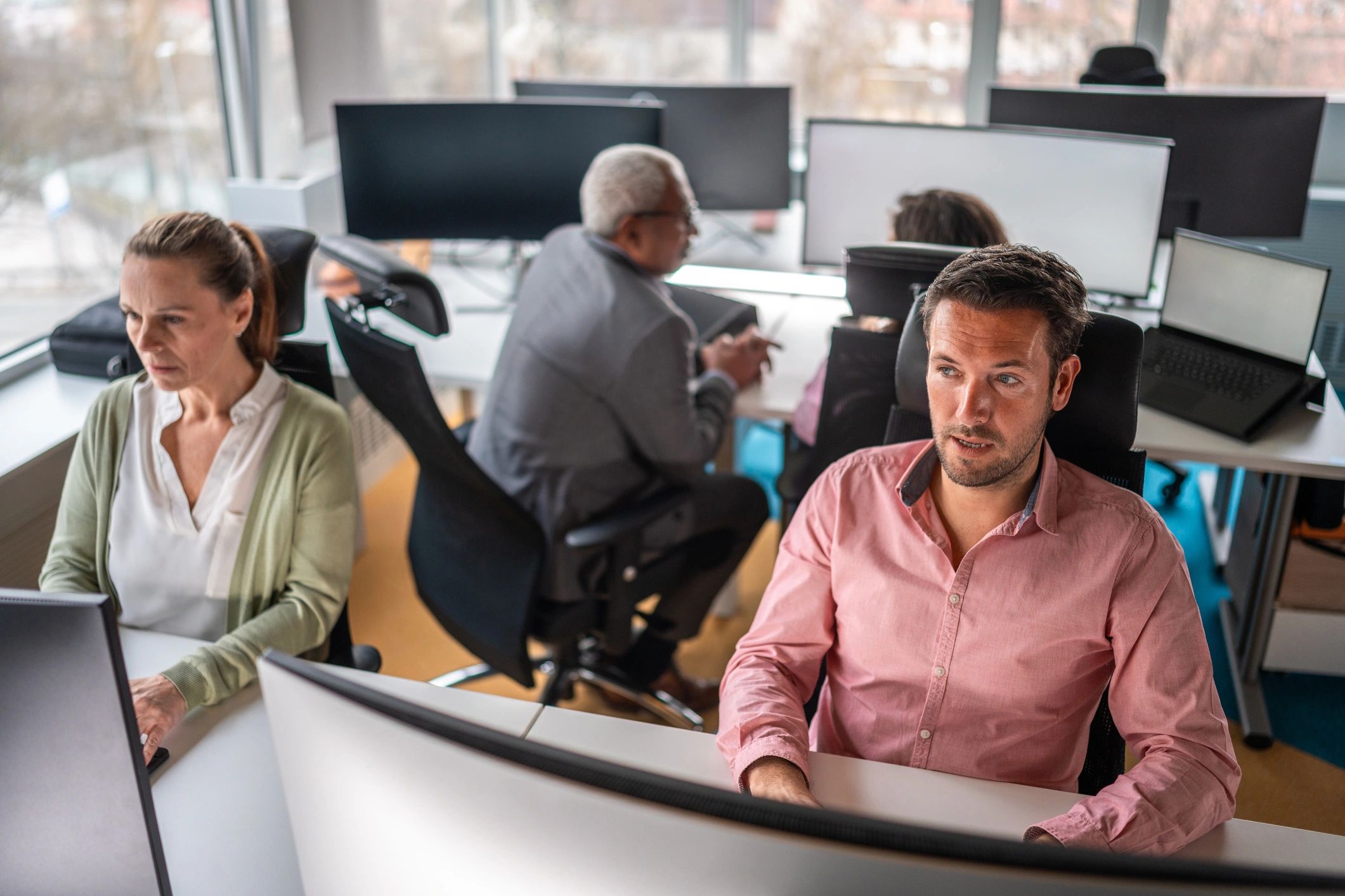 Professional IT support workspace with team members in the background